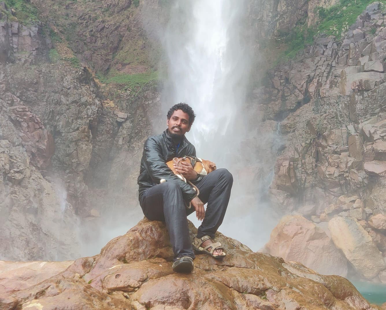 Ranjith sitting on a rock at the base of Nohkalikai Falls in Meghalaya, India