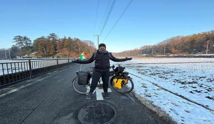Ranjith standing with his loaded touring bicycle on a snow-lined road